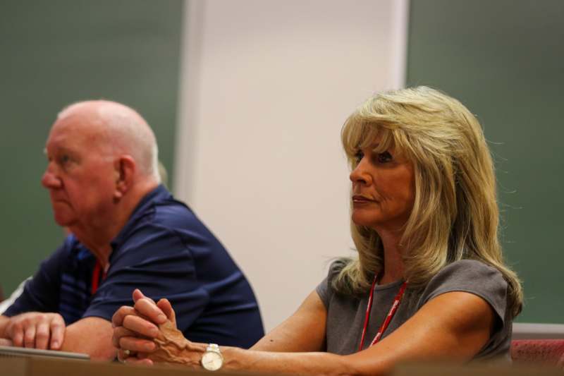 a woman sitting at a table with a man in the background