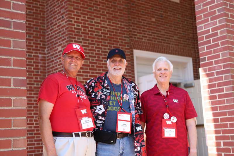 a group of men standing in front of a brick building