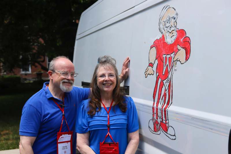 a man and woman standing next to a van with a cartoon on the side