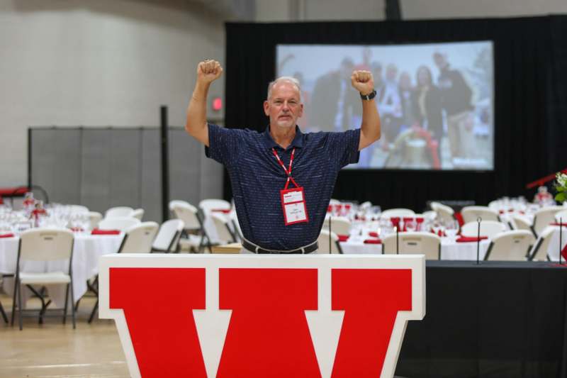 a man standing in front of a large sign with his hands up