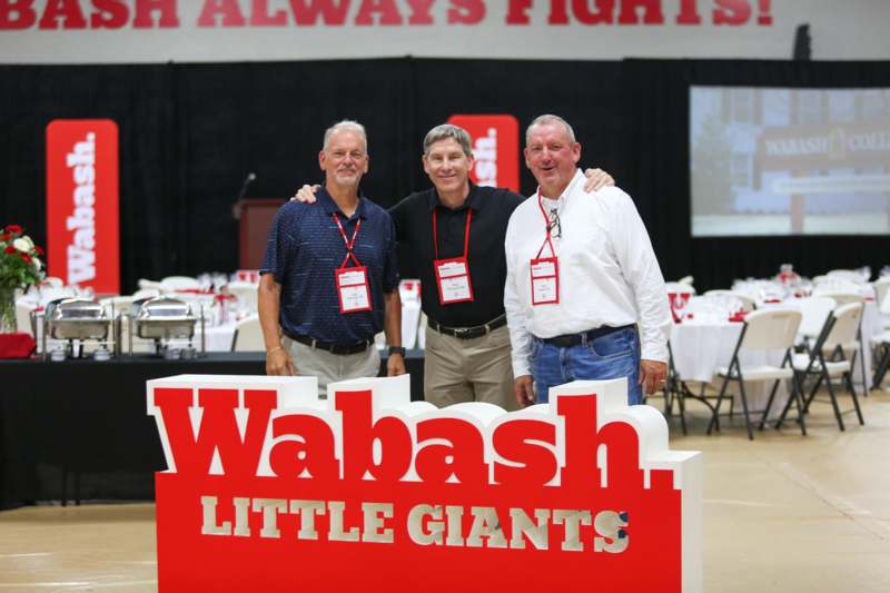 a group of men standing in front of a sign