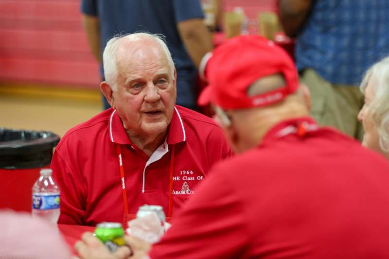 a man in red shirt talking to another man