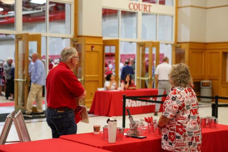 a man and woman standing in a room with red tablecloths