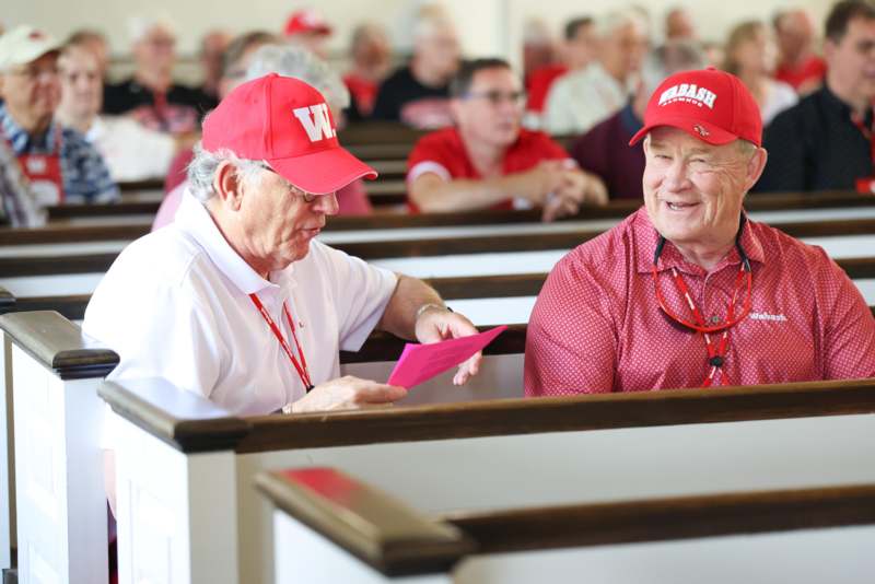 a group of men in red hats sitting in pews