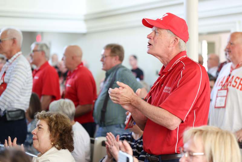 a man in a red hat speaking to a group of people
