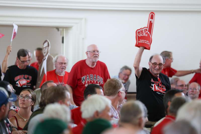a man holding a foam finger up in a room with people