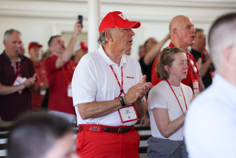 a man in red and white shirt standing in front of a group of people