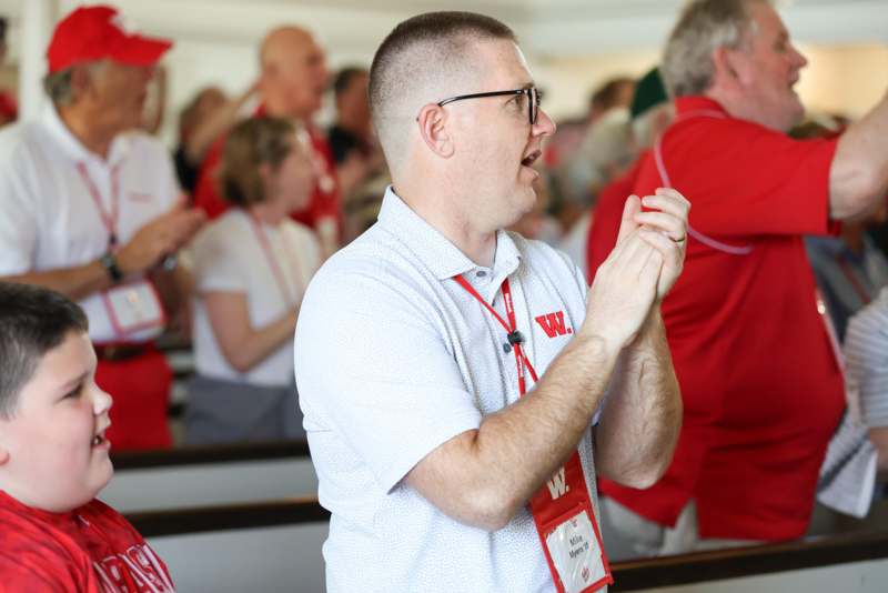 a man in a white shirt with a red badge and a white shirt with a white shirt and a red badge with a white shirt with a white shirt with a red badge on it