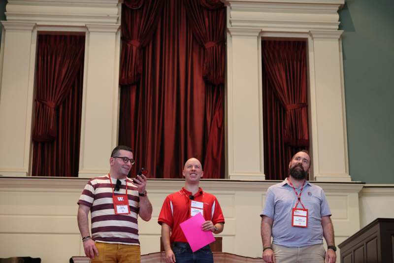 a group of men standing in front of a curtain