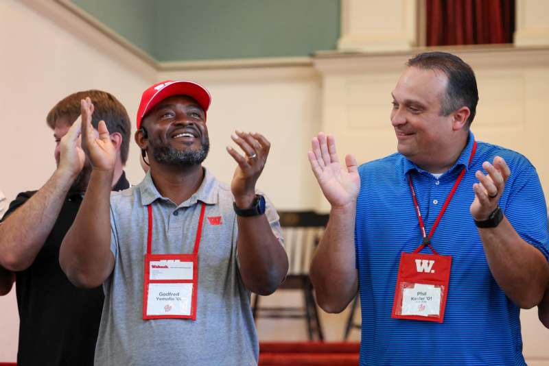 a group of men wearing lanyards and holding their hands up