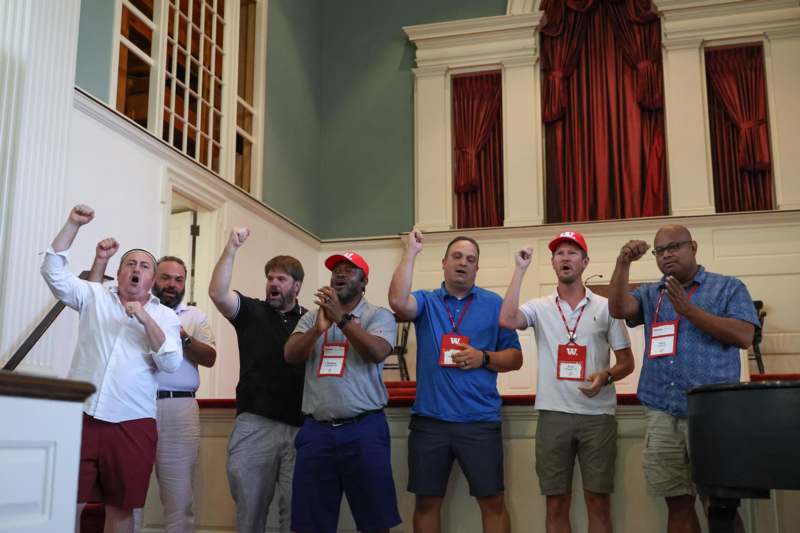 a group of people standing in a room with their hands up