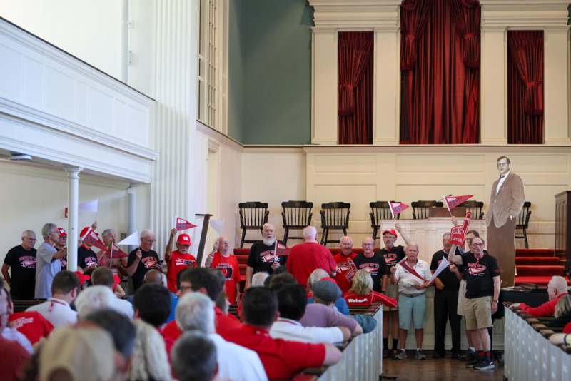 a group of people in a room with red curtains