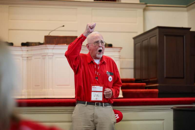 a man in a red shirt holding his hand up