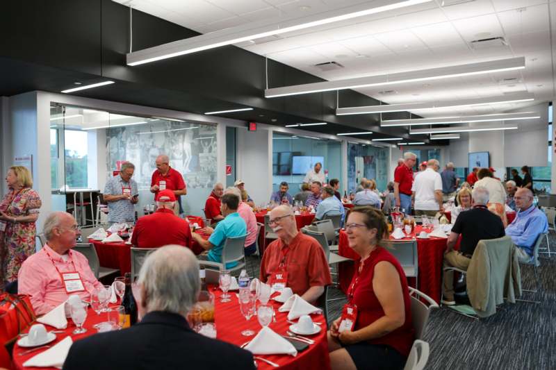 a group of people sitting at tables in a room with red tables and red tablecloths