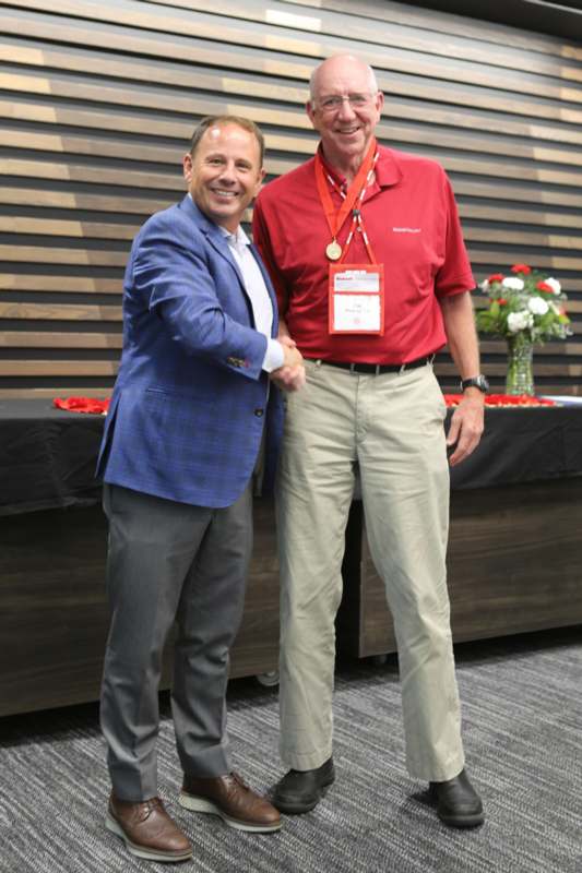 two men shaking hands in front of a wood wall