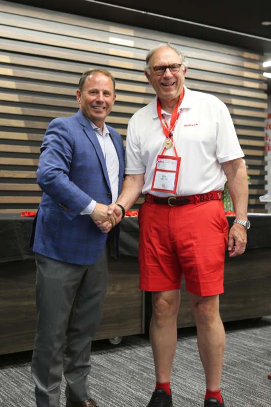 two men shaking hands in front of a wood wall