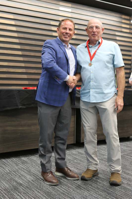 two men shaking hands in front of a wood wall
