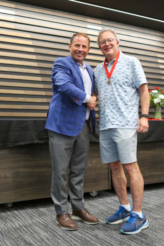 two men shaking hands in front of a wood wall
