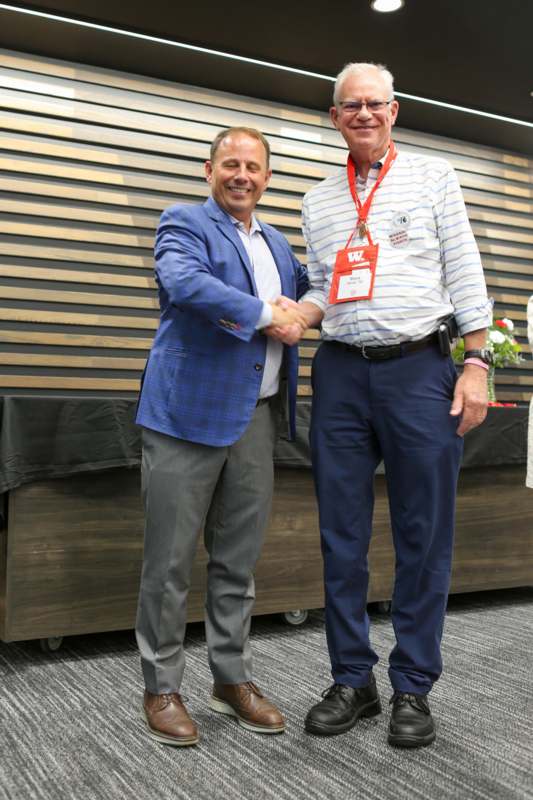 two men shaking hands in front of a wood wall