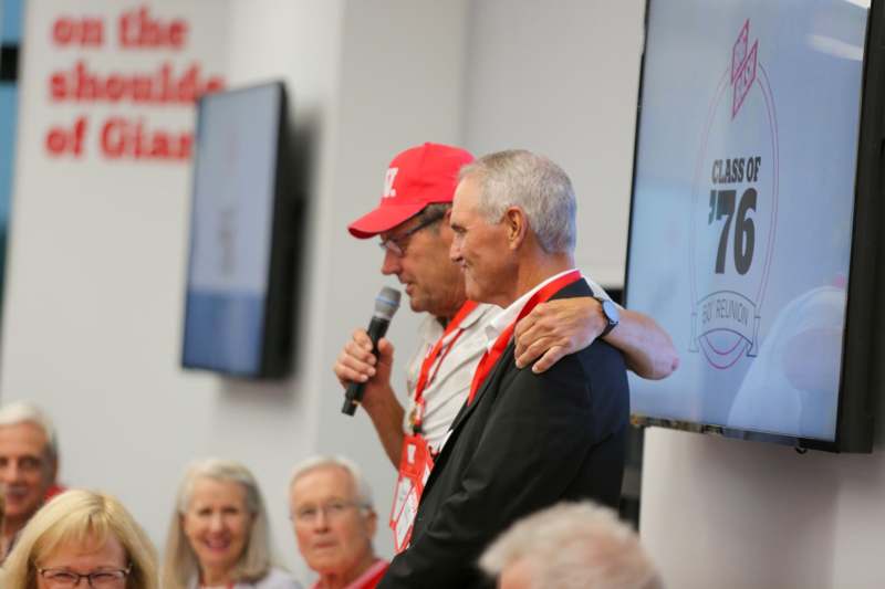 a man holding a microphone with another man in the background