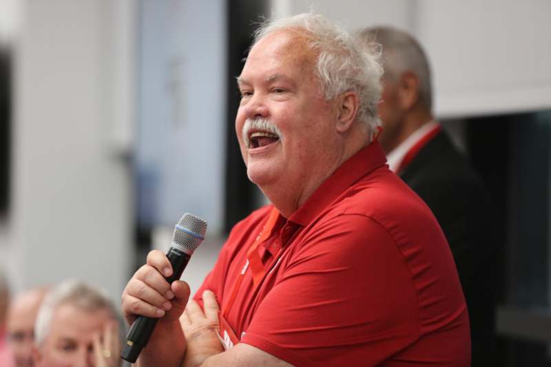 a man in a red shirt holding a microphone