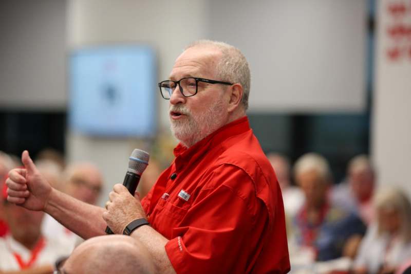 a man in a red shirt holding a microphone