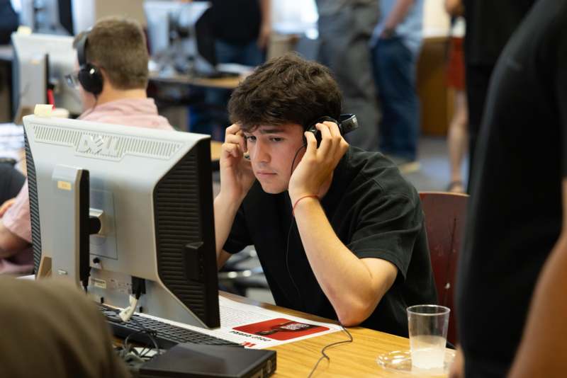 a man wearing headphones sitting at a desk with a computer