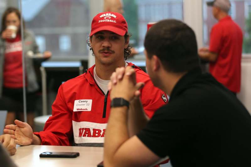 a man in a red hat talking to another man