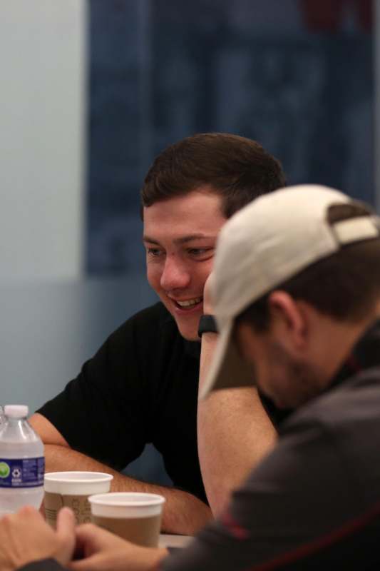 a man sitting at a table with another man in the background