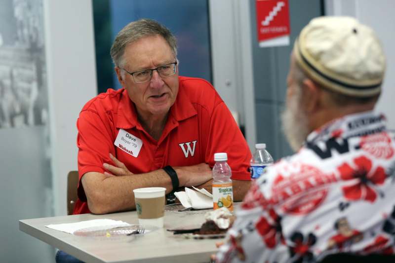 a man in red shirt talking to another man