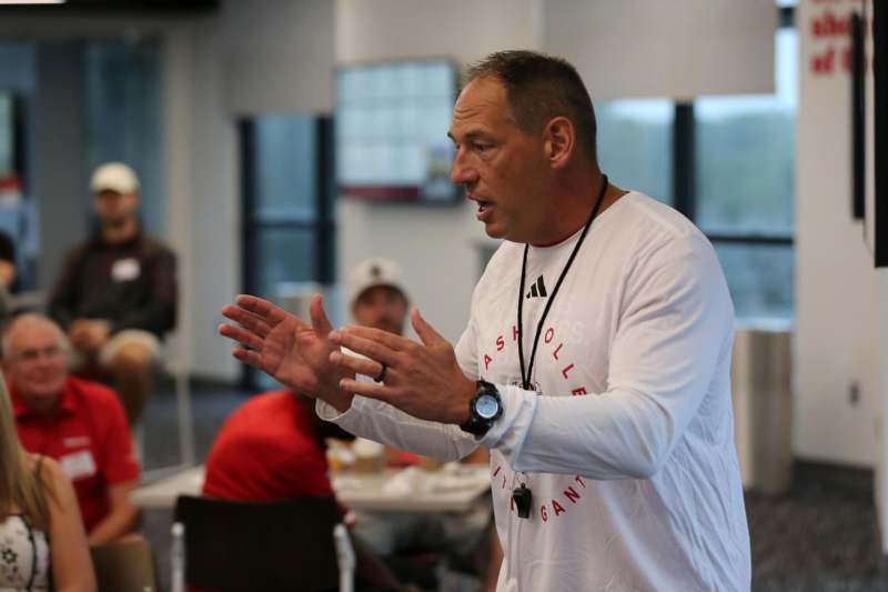 a man in a white shirt talking to a group of people