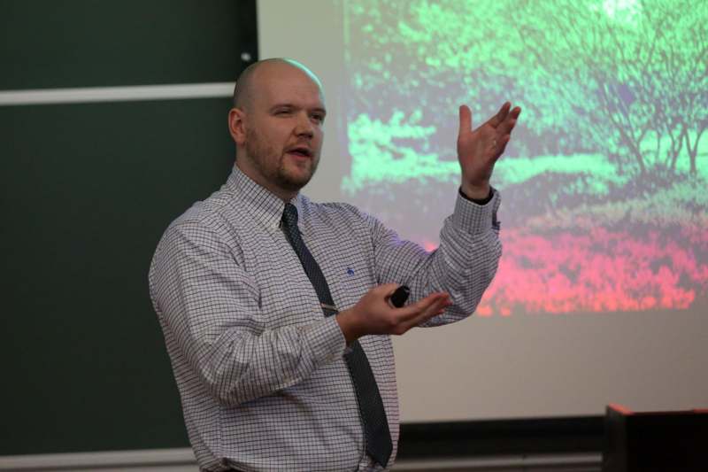 a man in a tie and tie standing in front of a projection screen