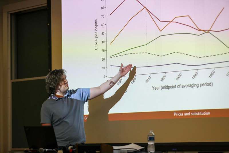 a man standing in front of a large screen pointing at a graph