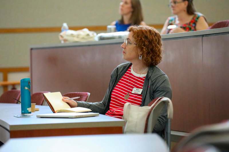 a woman sitting at a table with a book and a pen