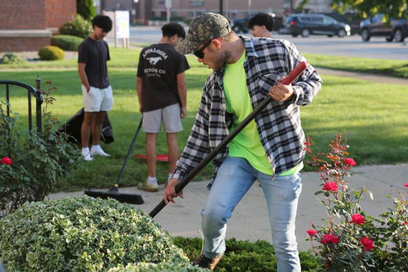 a man using a shovel to clean a bush