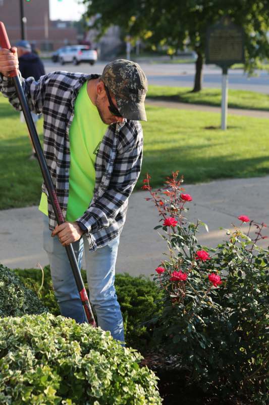 a man using a shovel to cut flowers