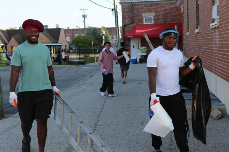 a group of men carrying paint and a ladder