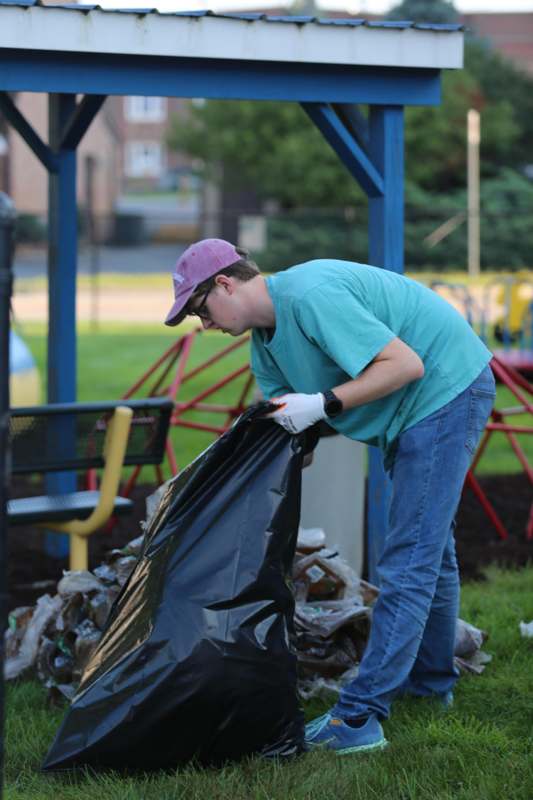 a man picking up garbage in a park
