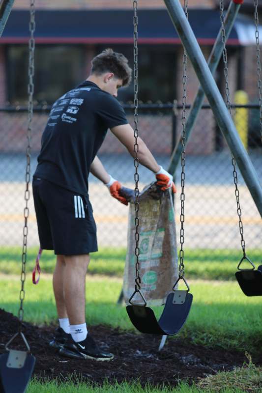 a man in gloves picking up a bag of trash