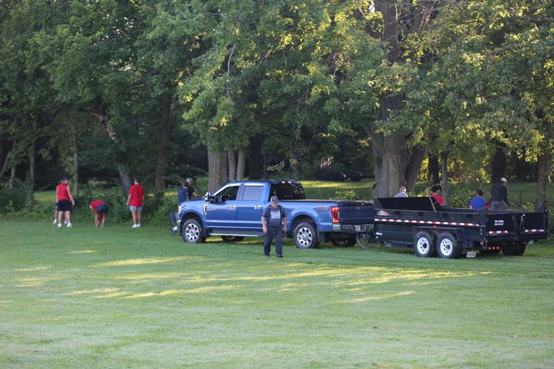 a blue truck with a trailer in a grassy area with people