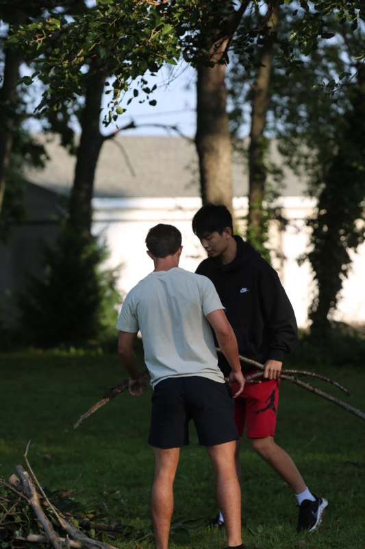 two men holding sticks in a yard