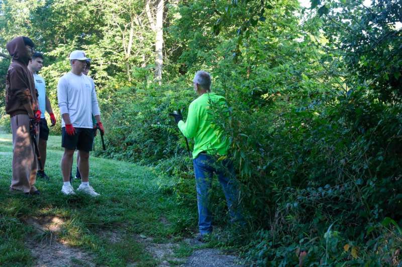 a man and woman standing on a path in the woods