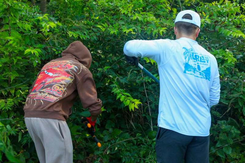 a man in a hoodie cutting a tree