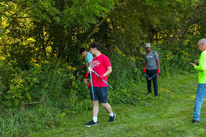 a group of men holding tools in a grassy area