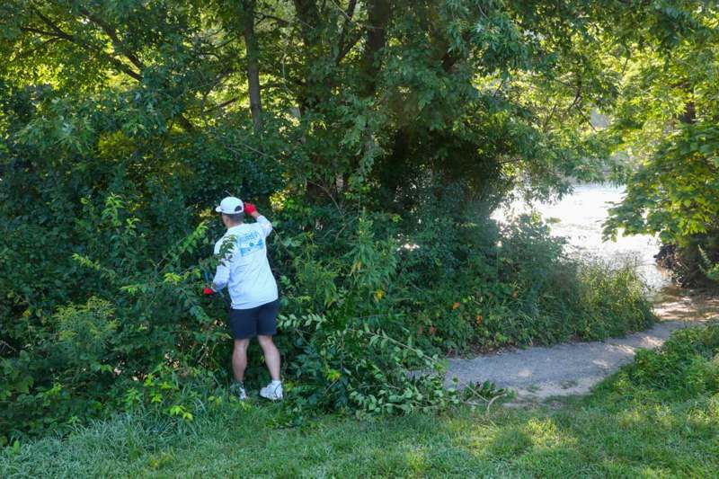 a man in a white shirt and black shorts standing next to a tree