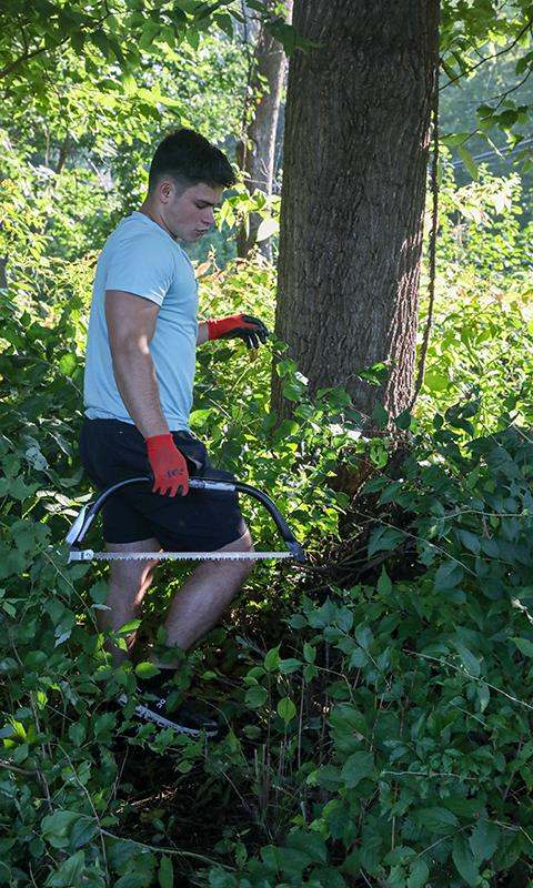 a man holding a saw in the woods