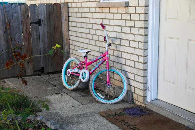 a pink and blue bicycle leaning against a brick wall