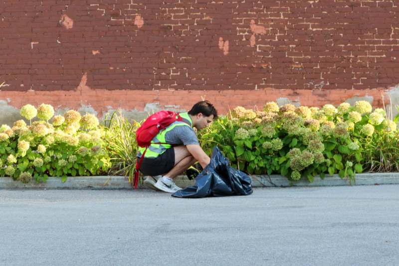a man picking up garbage in a bag