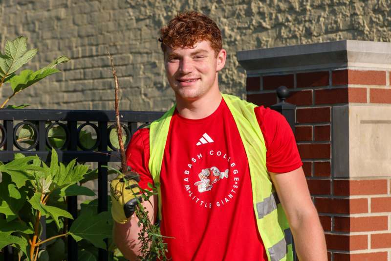a man wearing a safety vest and gloves holding a plant
