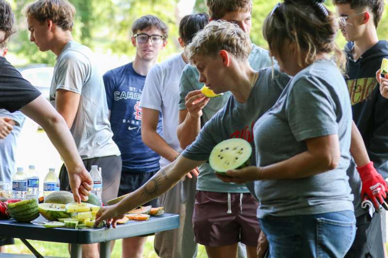 a group of people standing around a table with food
